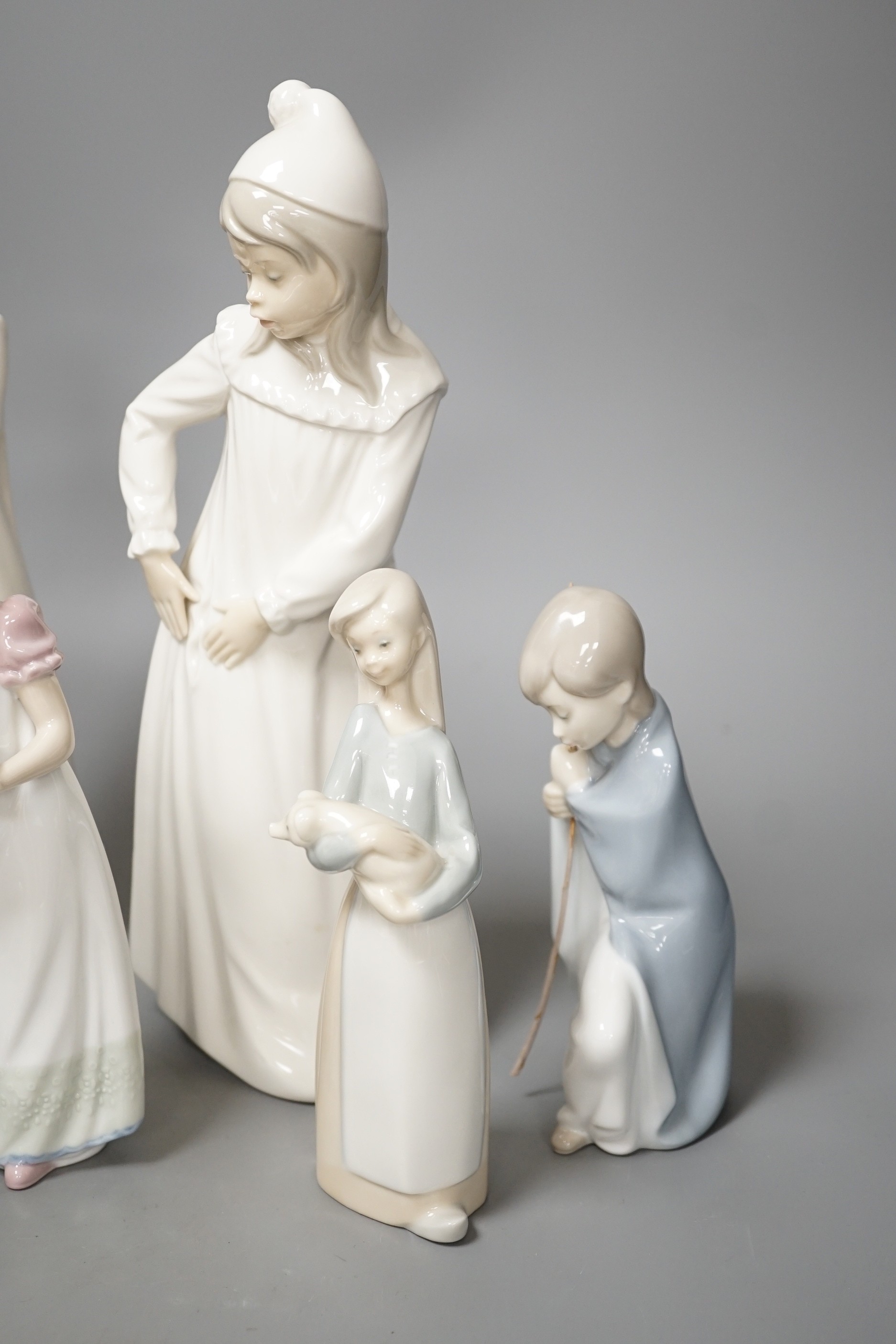 Seven Lladro figures together with two Nao figures. Tallest 29cm